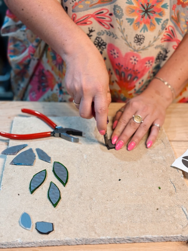 Person working on a craft project with floral-patterned fabric and tools on a wooden surface.