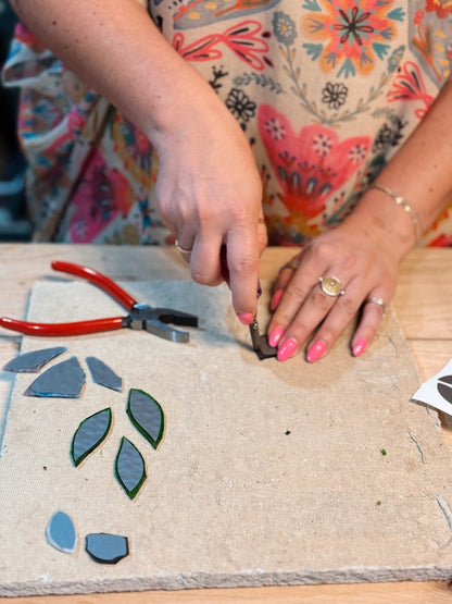 Person working on a craft project with floral-patterned fabric and tools on a wooden surface.